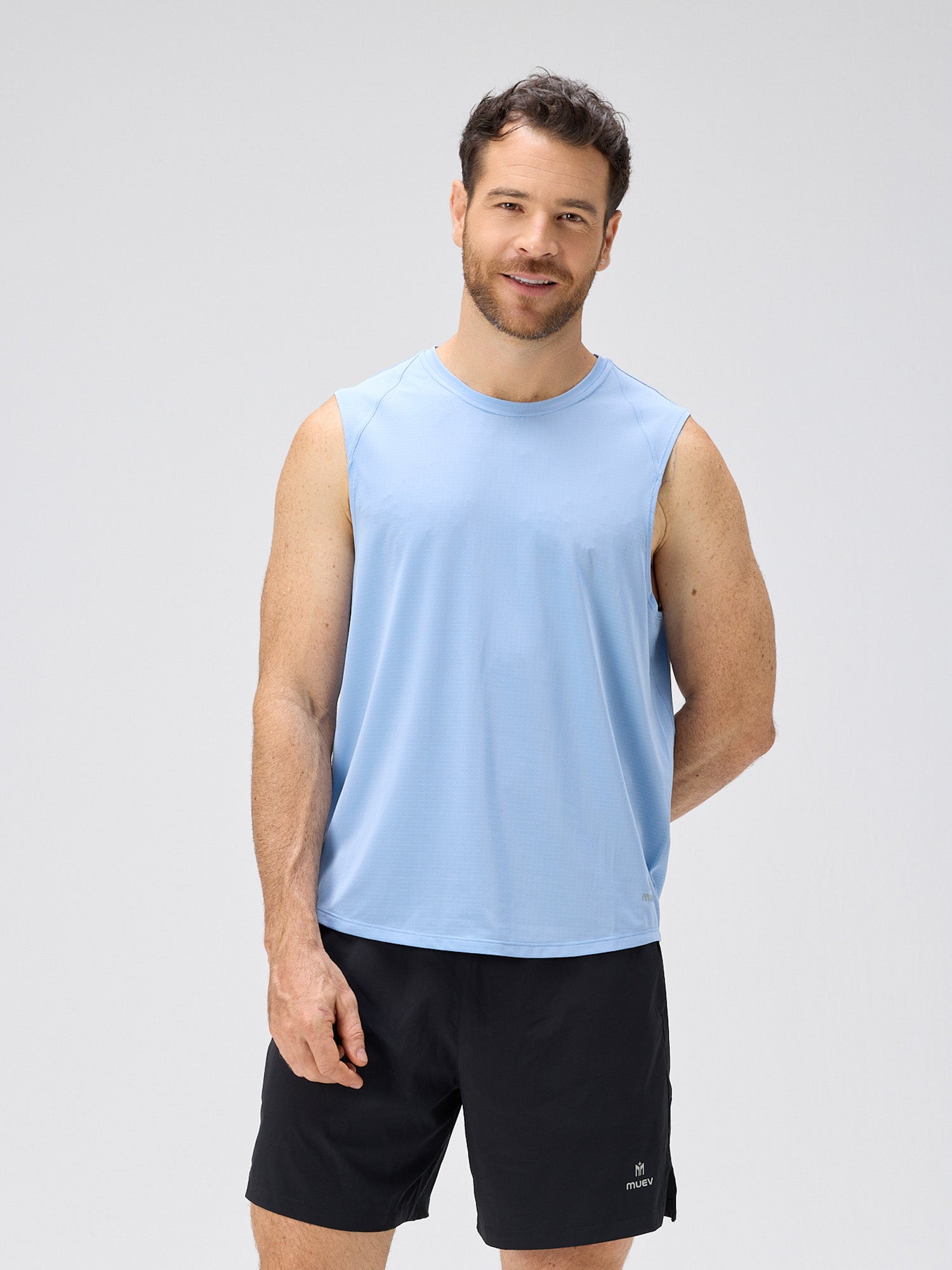 Man wearing a cloud blue sleeveless lightweight moisture-wicking stretch jersey paired with black shorts for padel and pickleball apparel.