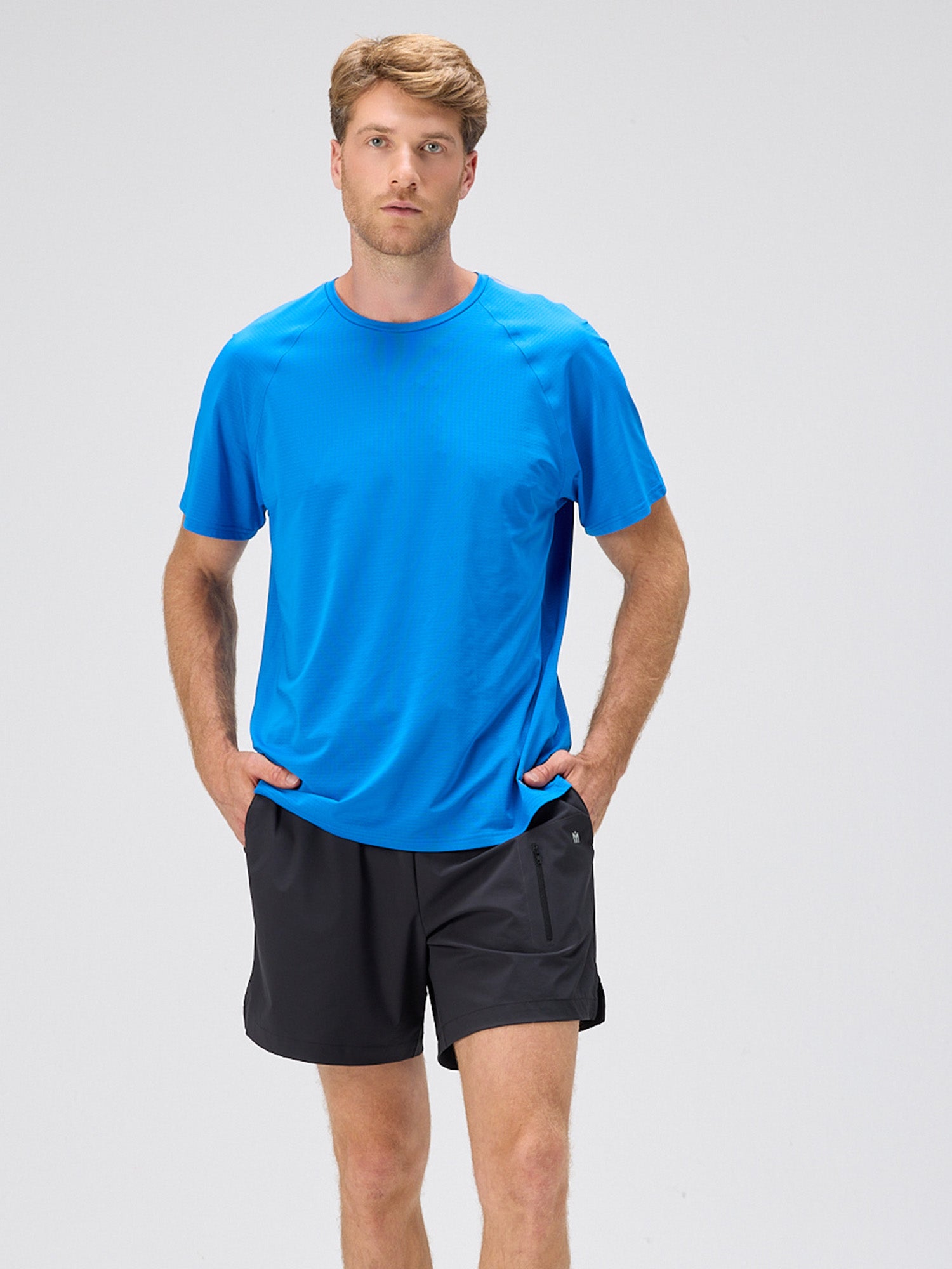 man wearing royal blue lightweight moisture-wicking stretch jersey tee with black shorts, styled for pickleball and padel apparel