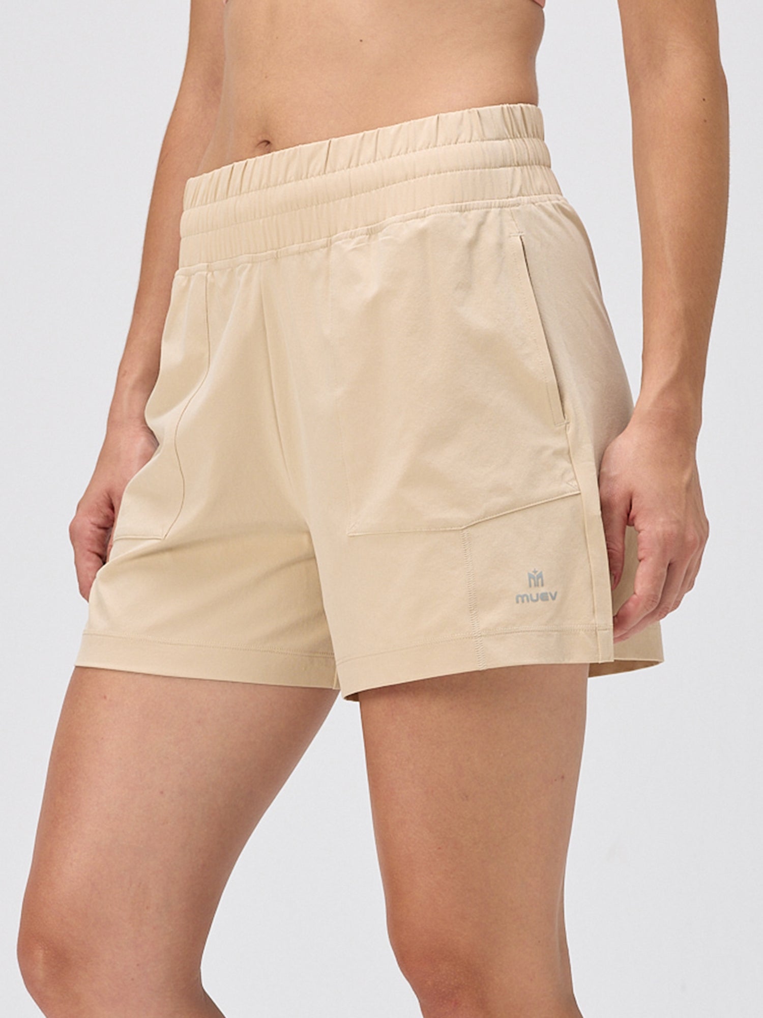 Close-up of khaki moisture-wicking shorts with an elastic waistband and side pockets, designed for padel and pickleball by MUEV