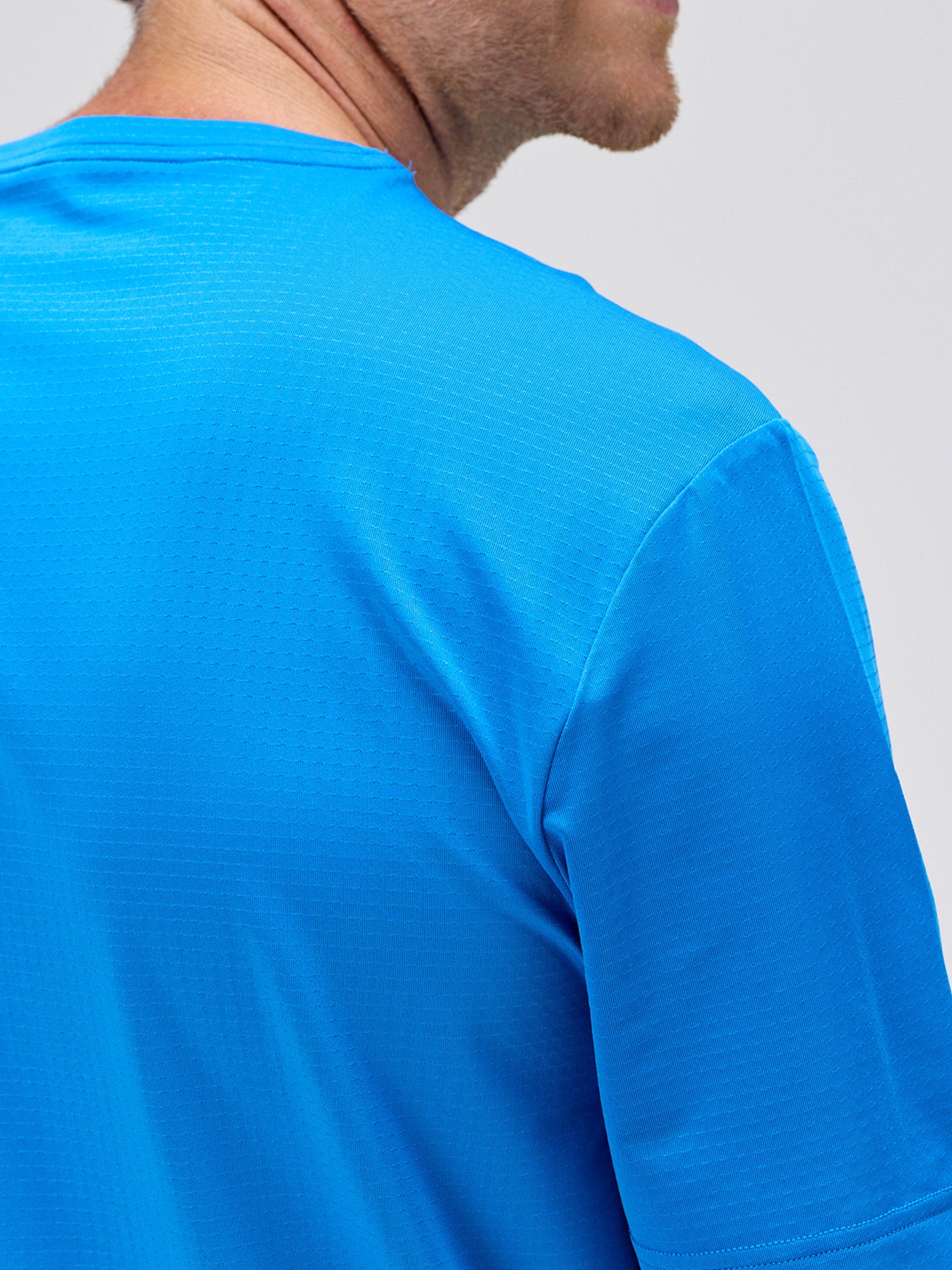 close-up of man wearing royal blue breathable performance tee with horizontal micro perforations designed for padel and pickleball apparel