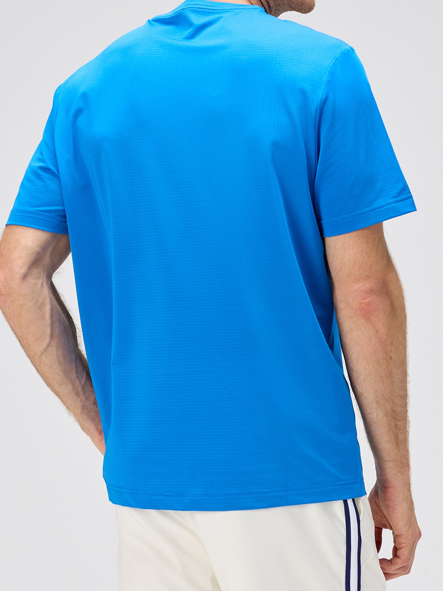 man wearing royal blue breathable moisture-wicking athletic shirt viewed from back, styled for pickleball and padel clothing
