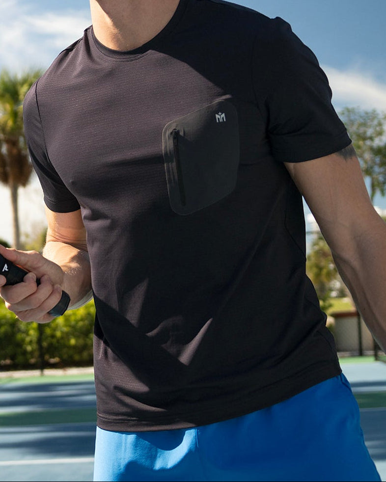 Two men on a pickleball court holding paddles and a ball, with palm trees in the background.
