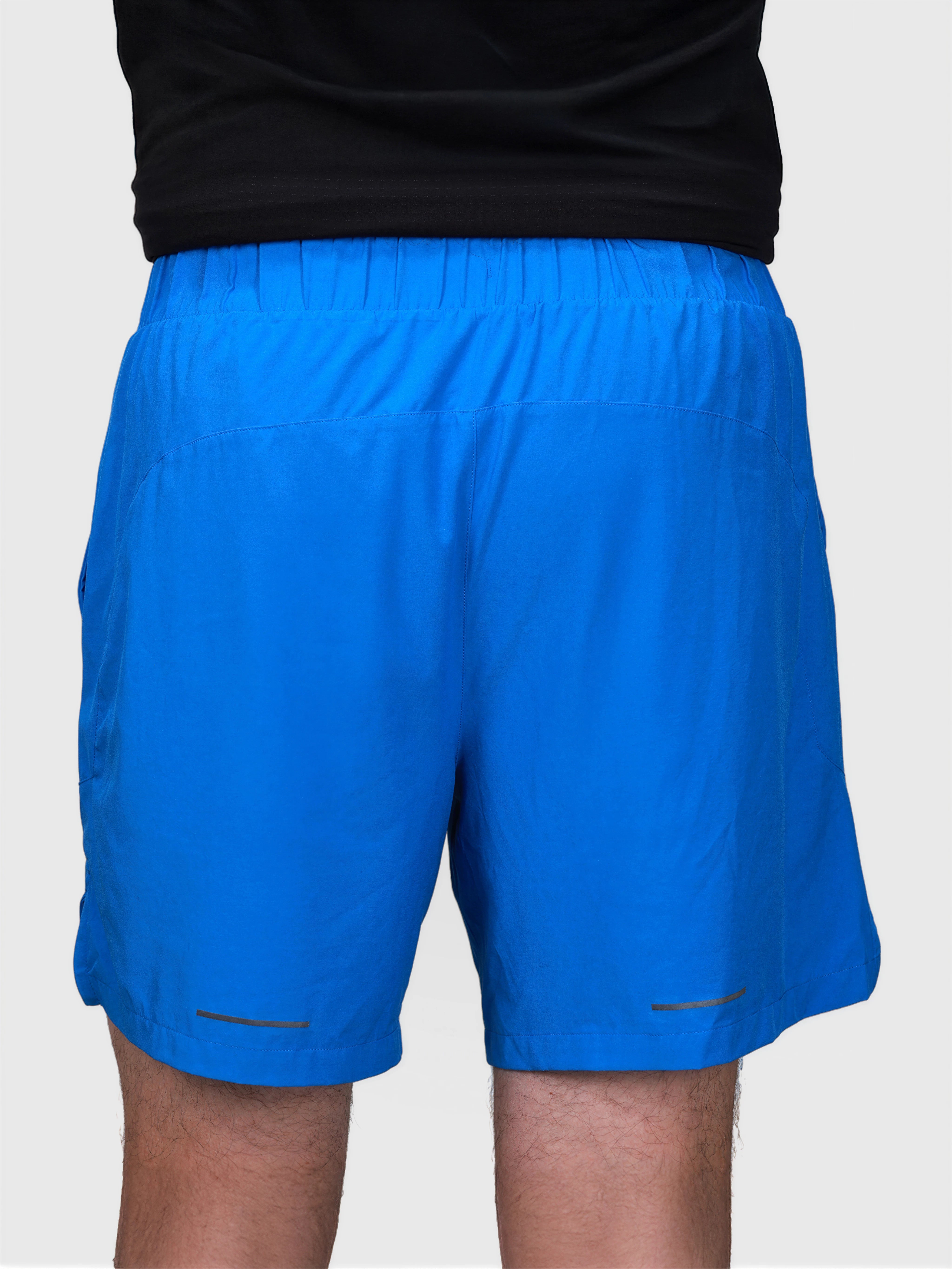 Back view of man wearing bright blue Base Line shorts with elastic waistband in padel apparel by MUEV
