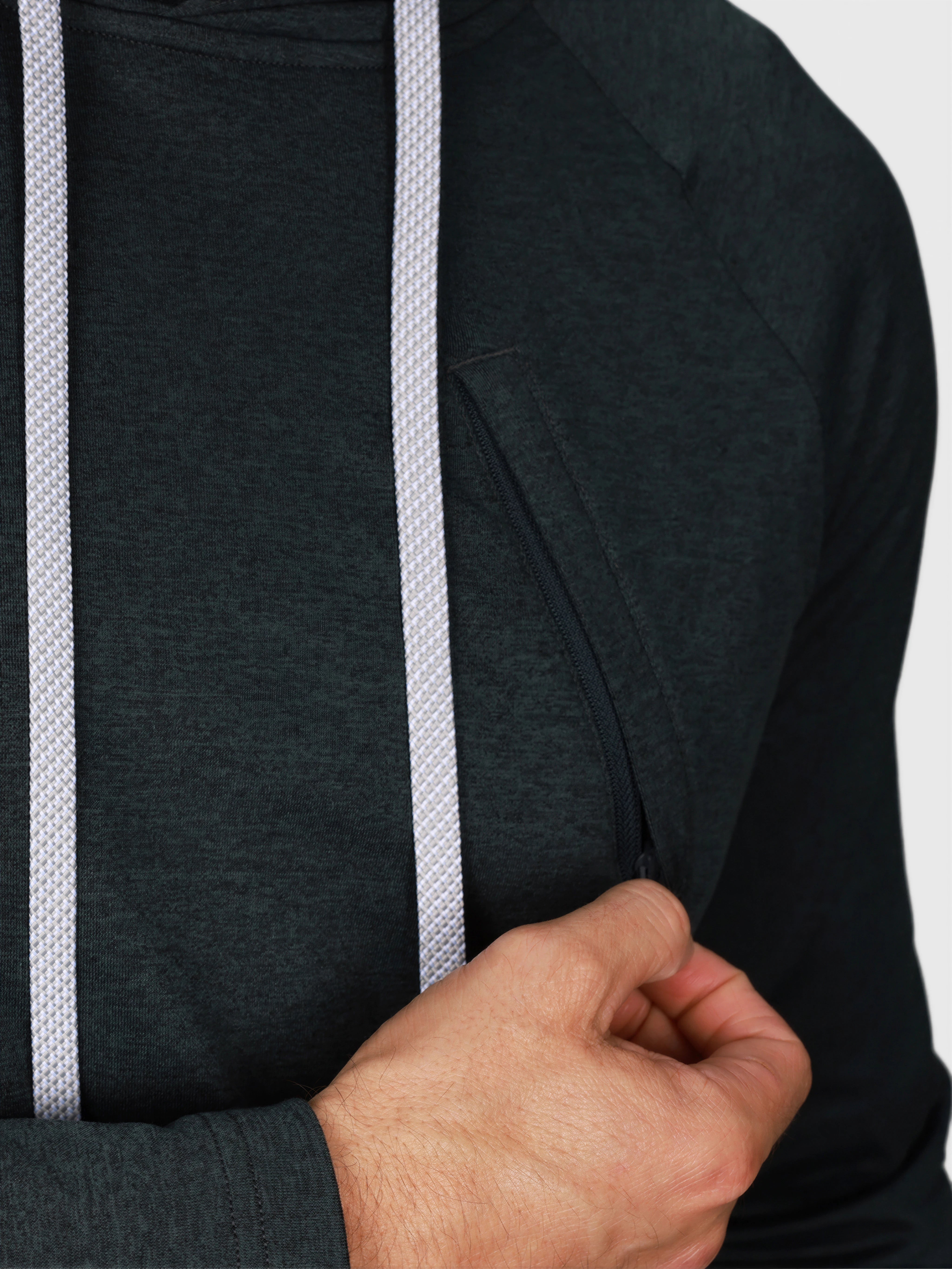 Close-up showing hand pulling zipper on Heather Charcoal Pro Serve Hoodie by MUEV for padel clothing