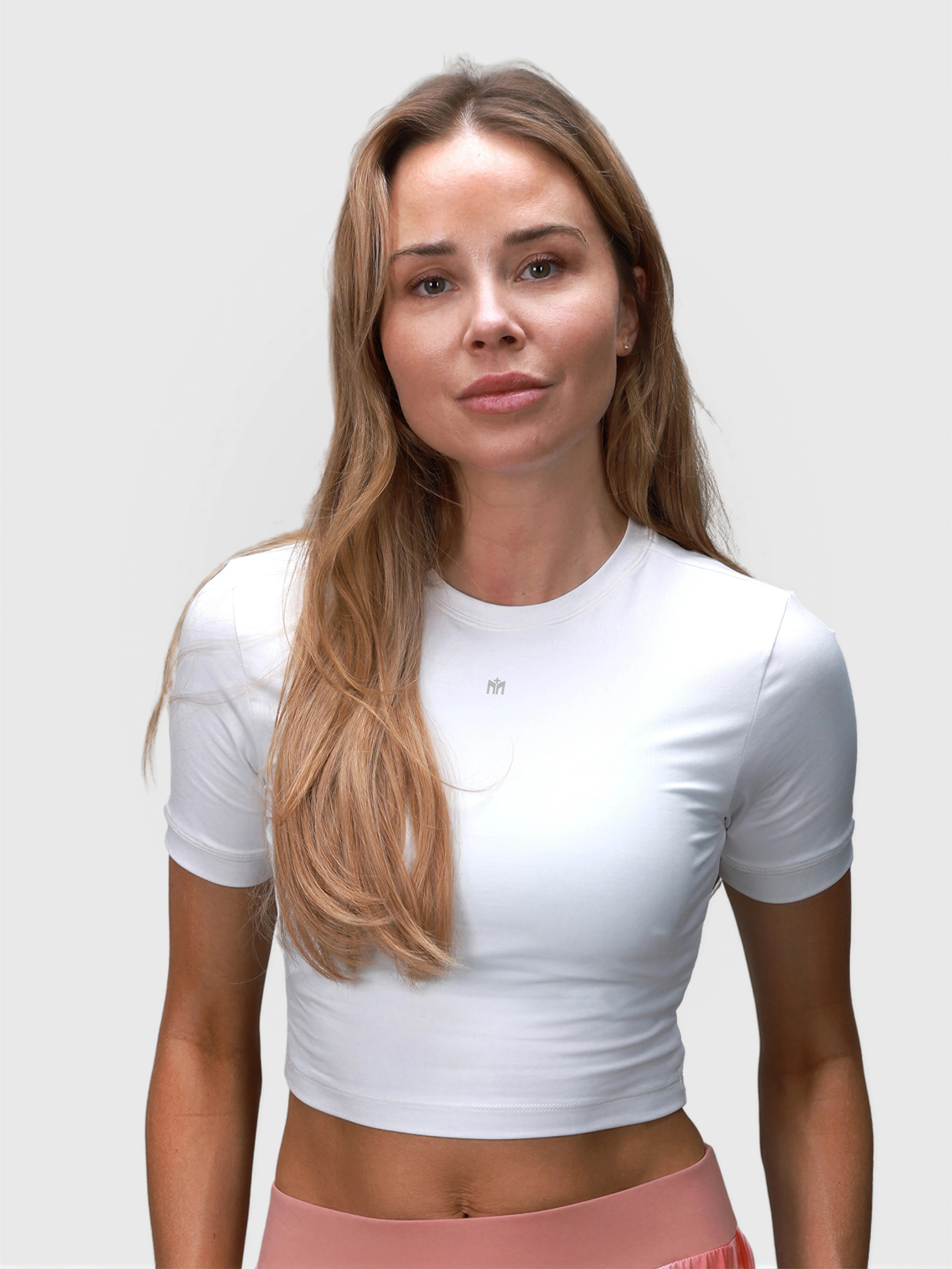 Woman wearing white Kamryn Cropped Tee by MUEV designed for padel and pickleball clothing