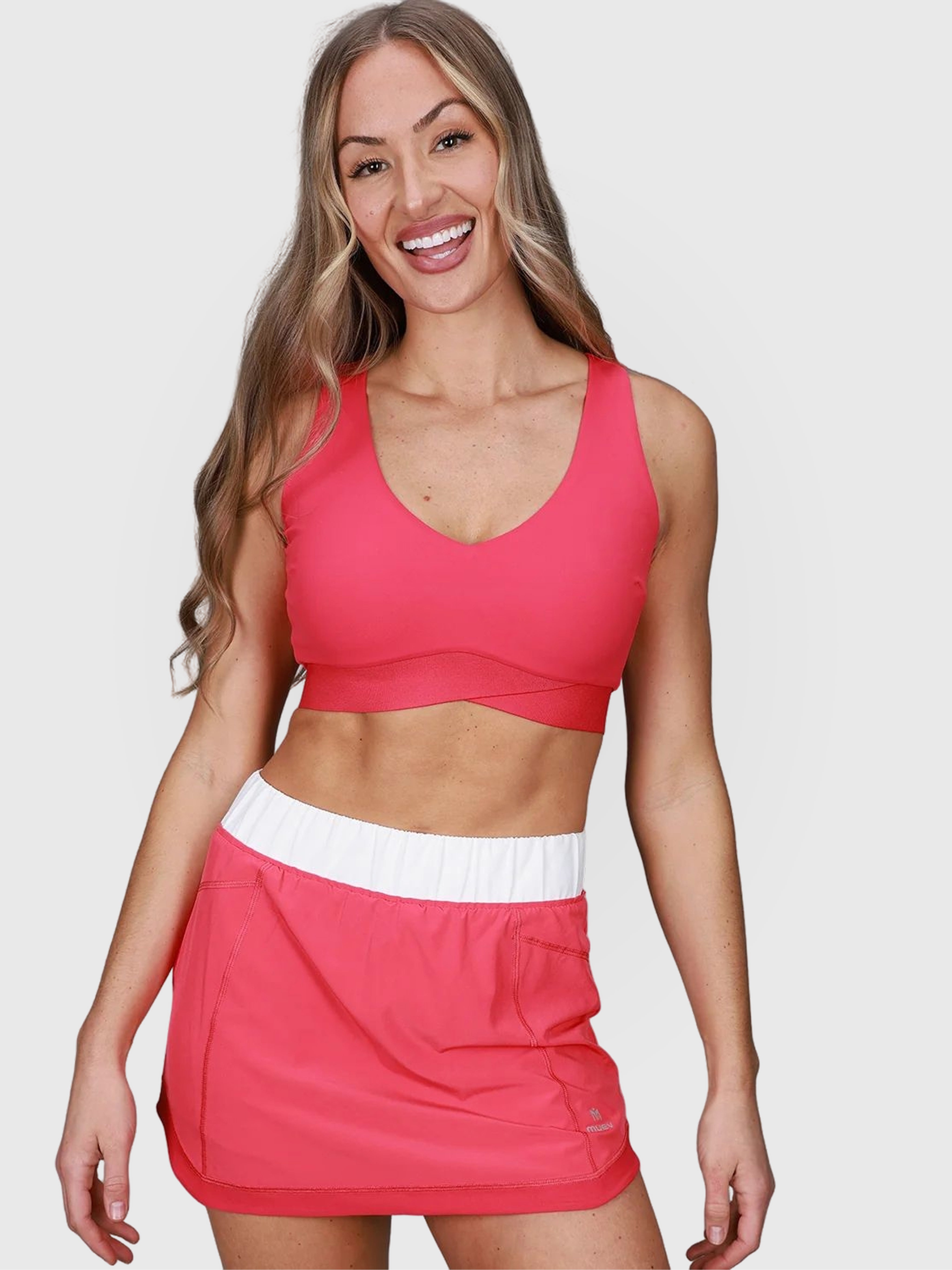 woman smiling wearing pink Performance Skort with white waistband for padel and pickleball apparel by MUEV