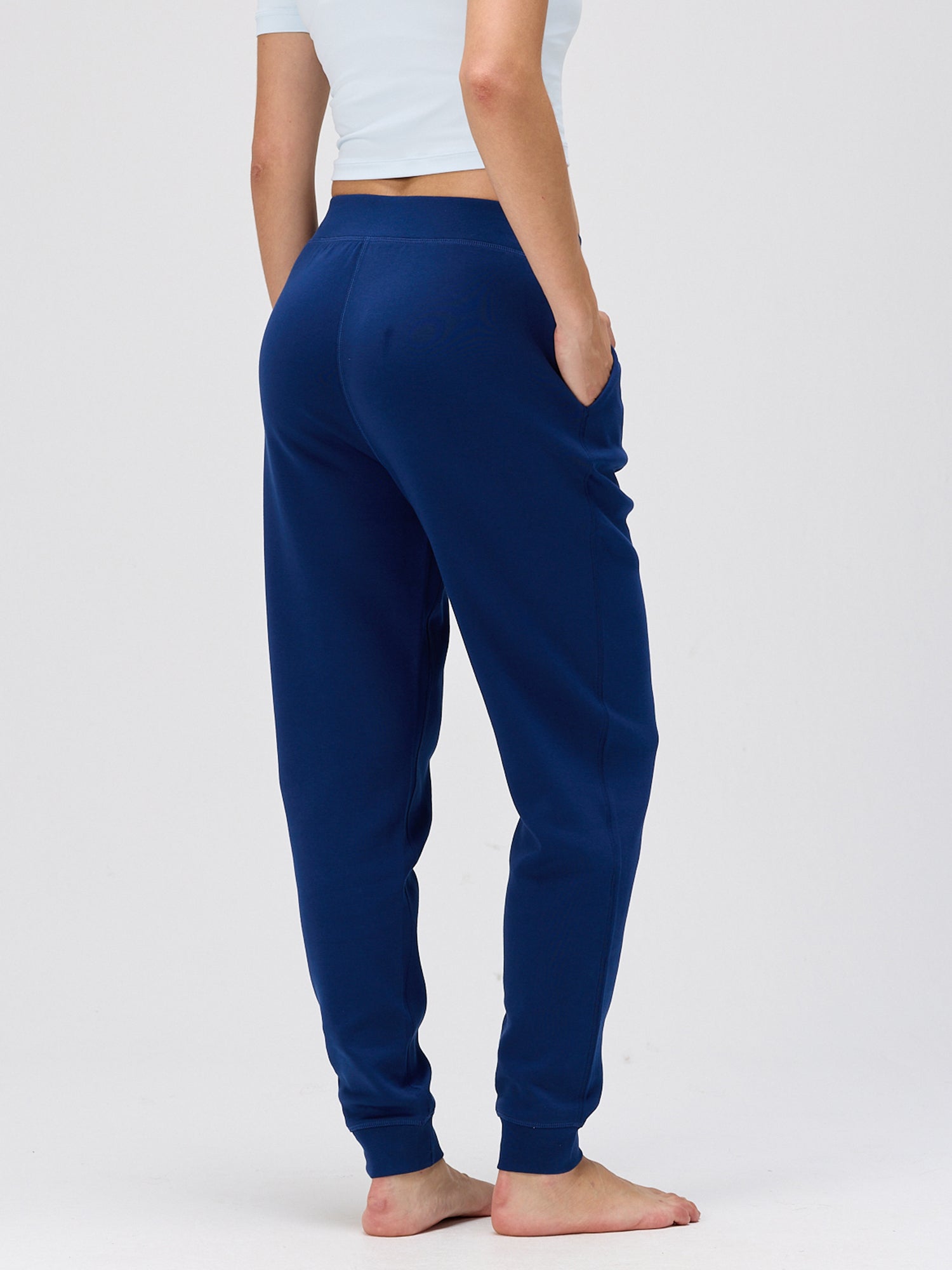 woman wearing navy casual resort pants with elastic waistband and side pockets standing barefoot against plain background