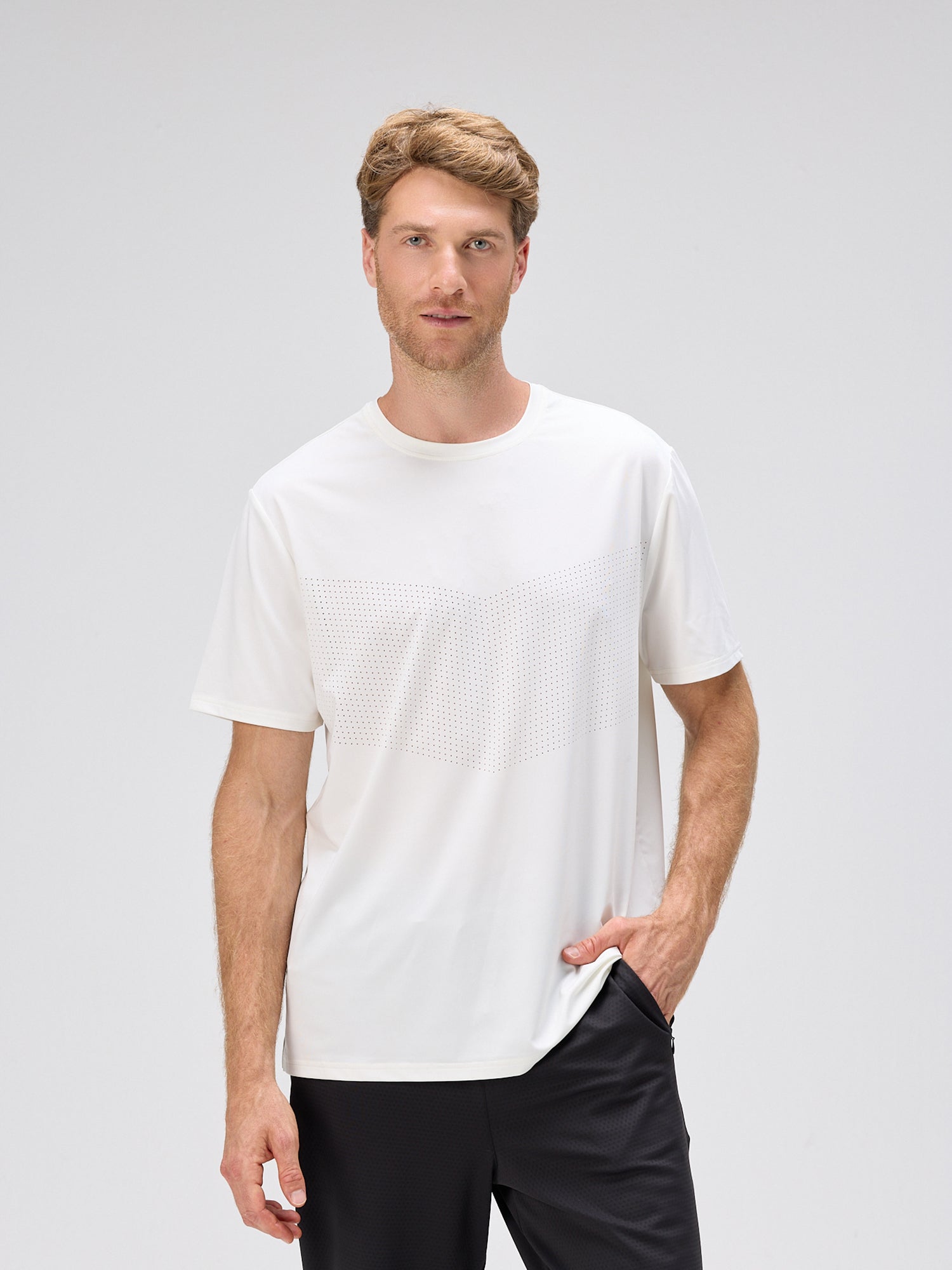 Man wearing a white athletic tee with laser perforation for cooling, moisture-wicking fabric, and SPF 50, paired with black shorts.