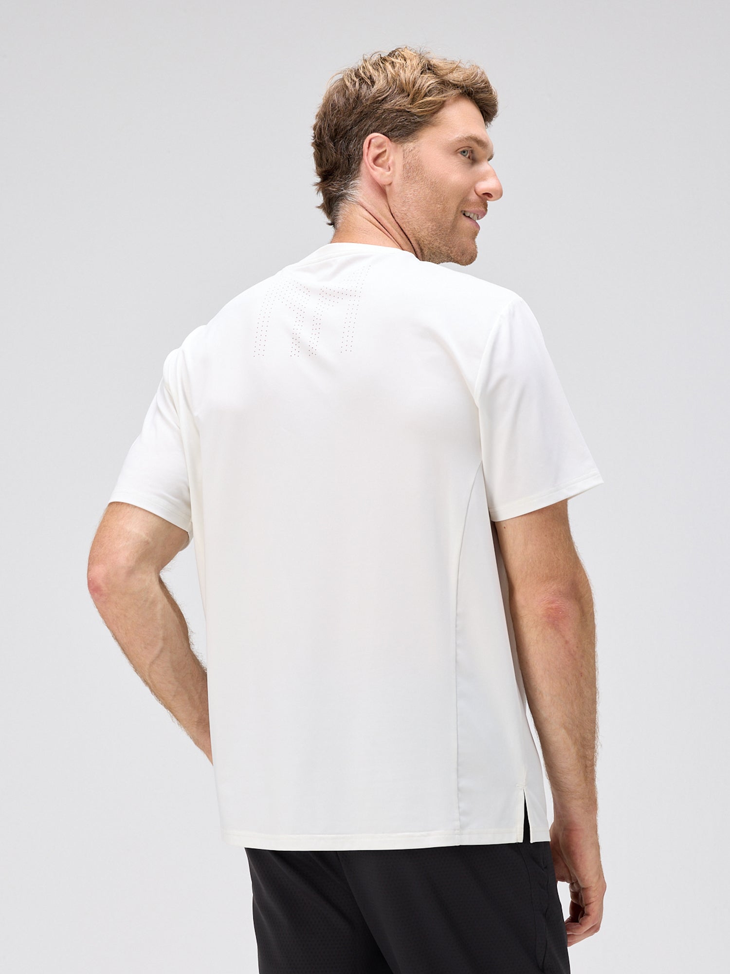 Man wearing a white chevron pattern athletic shirt with laser perforation for cooling, moisture-wicking fabric, and SPF 50 protection.