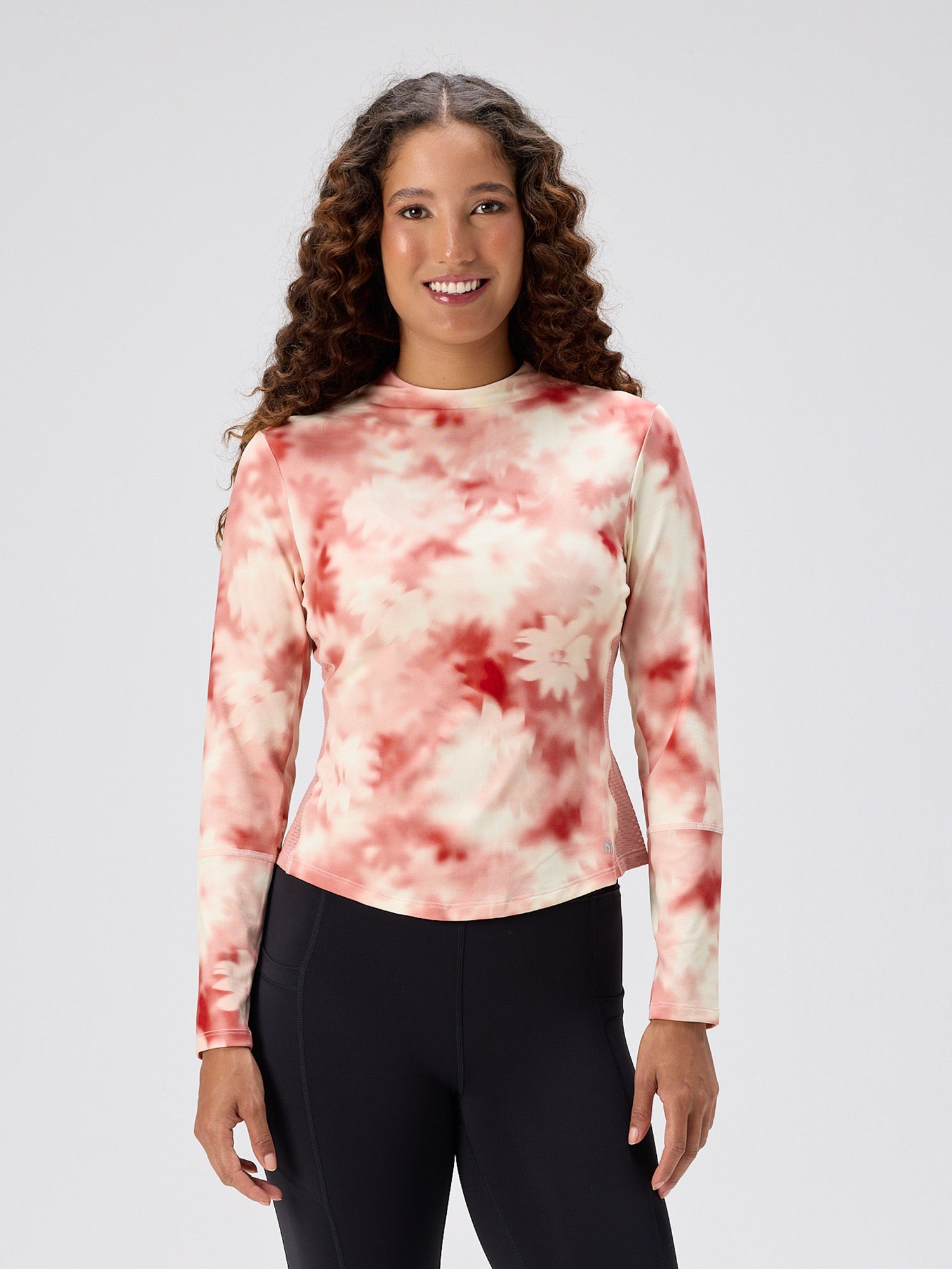 woman wearing long-sleeve moisture-wicking pink petal patterned top with mesh back panel paired with black athletic leggings for pickleball and padel apparel