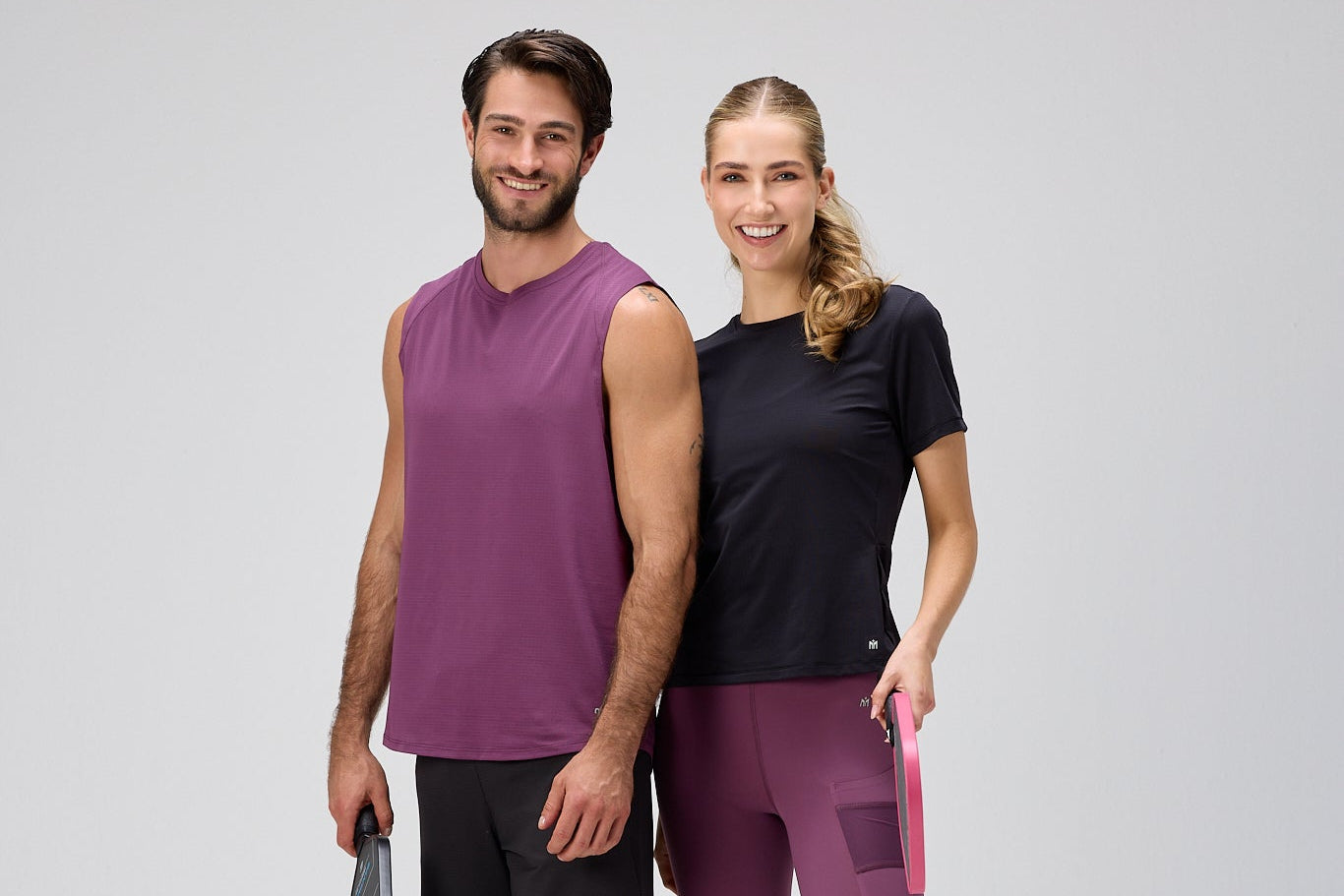 Man and woman in matching athletic wear standing side by side on a white background