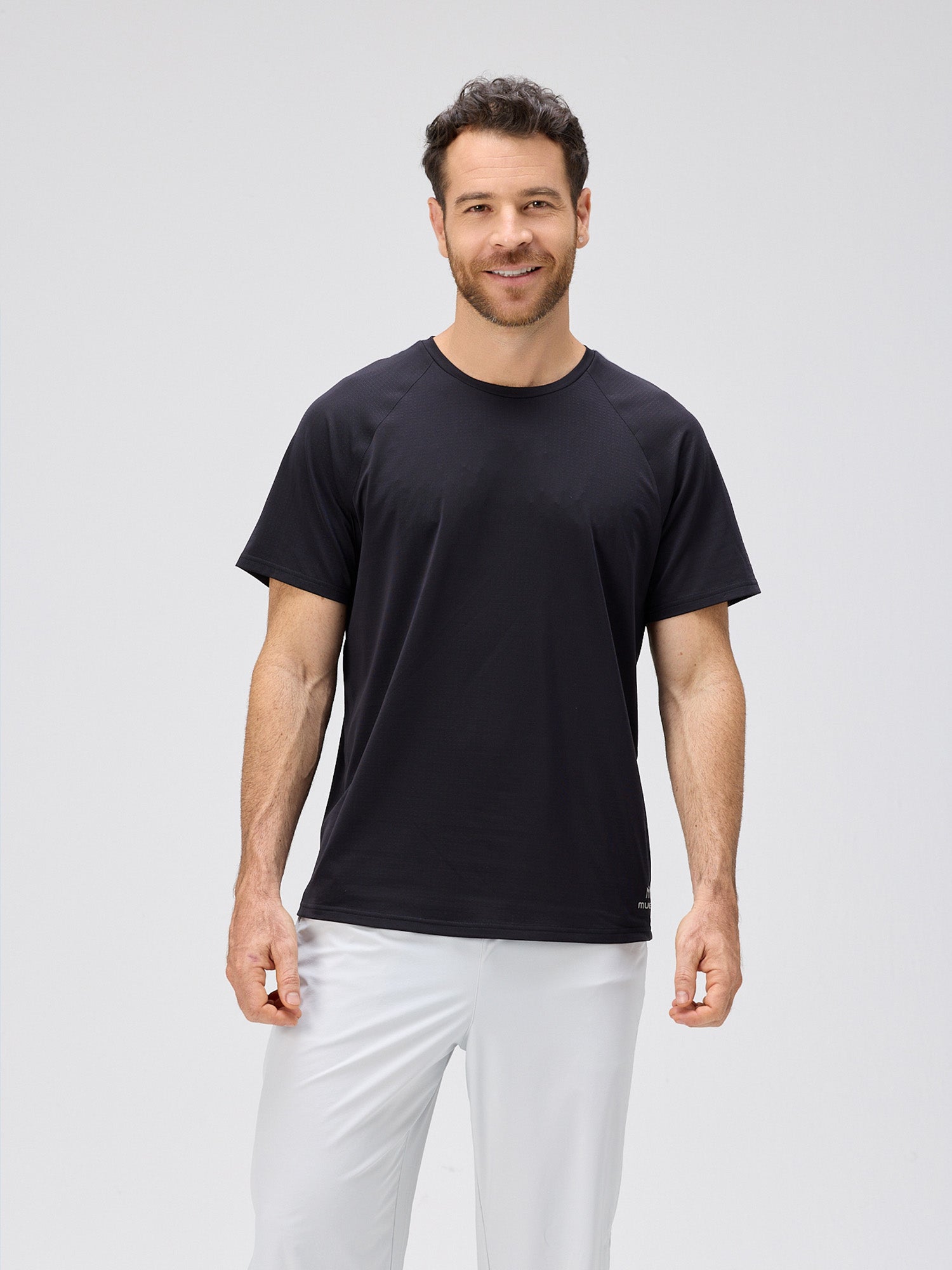 Man wearing a black lightweight moisture-wicking stretch jersey tee with bonded seams, designed for padel and pickleball apparel.