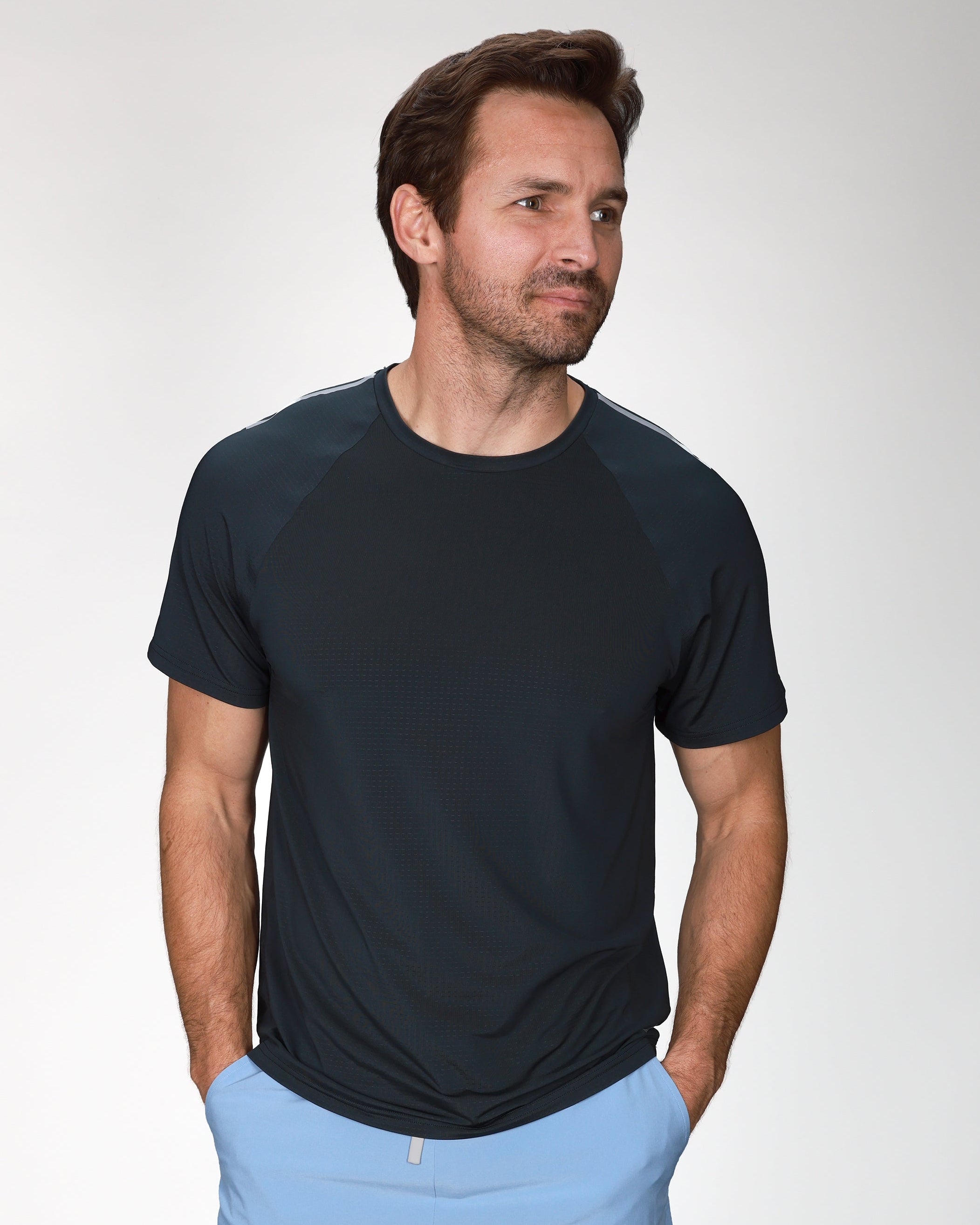 Man wearing a black t-shirt and light blue shorts on a white background