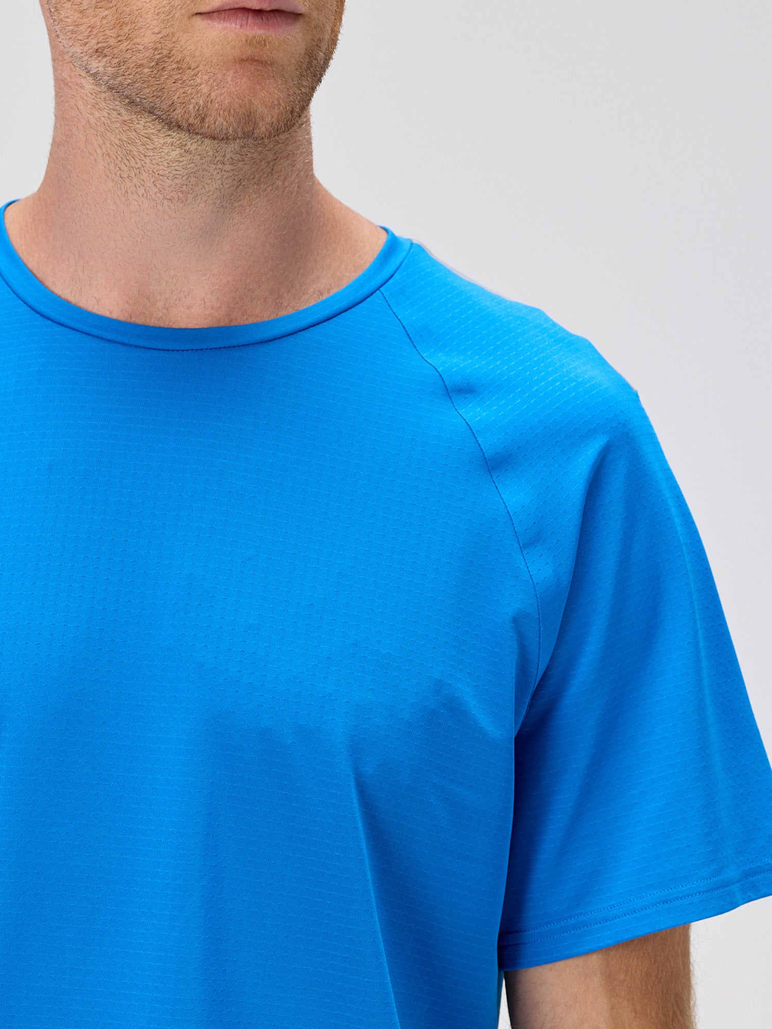 Close-up of man wearing royal blue lightweight moisture-wicking performance tee with horizontal micro-perforations for breathability designed for pickleball apparel.