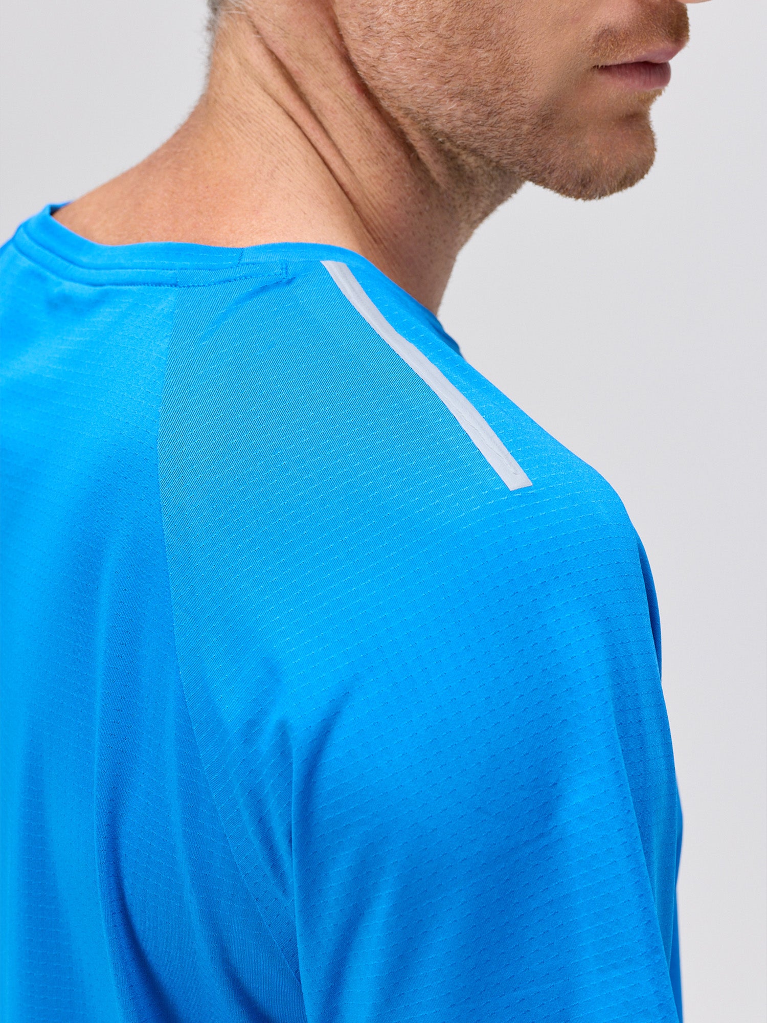 close-up of man wearing royal blue lightweight moisture-wicking pickleball shirt with micro-perforations and bonded seams