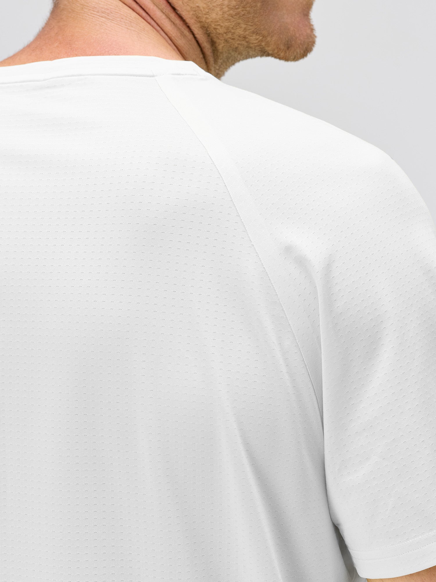 Close-up of a white lightweight moisture-wicking stretch jersey with horizontal micro-perforations and bonded seams for enhanced airflow in padel and pickleball apparel