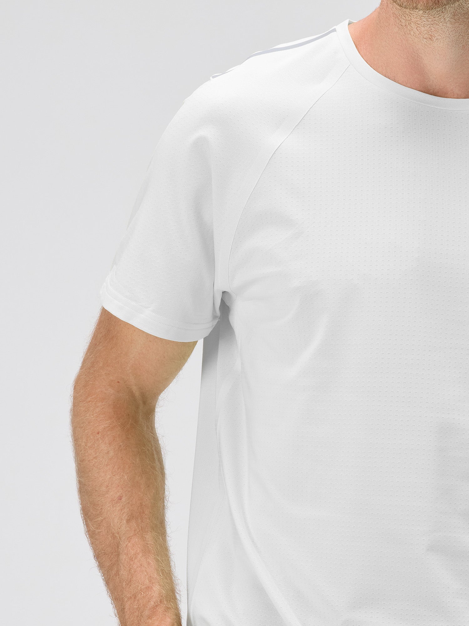 Close-up of a man wearing a white lightweight moisture-wicking stretch jersey with bonded seams and micro-perforations for padel and pickleball clothing.