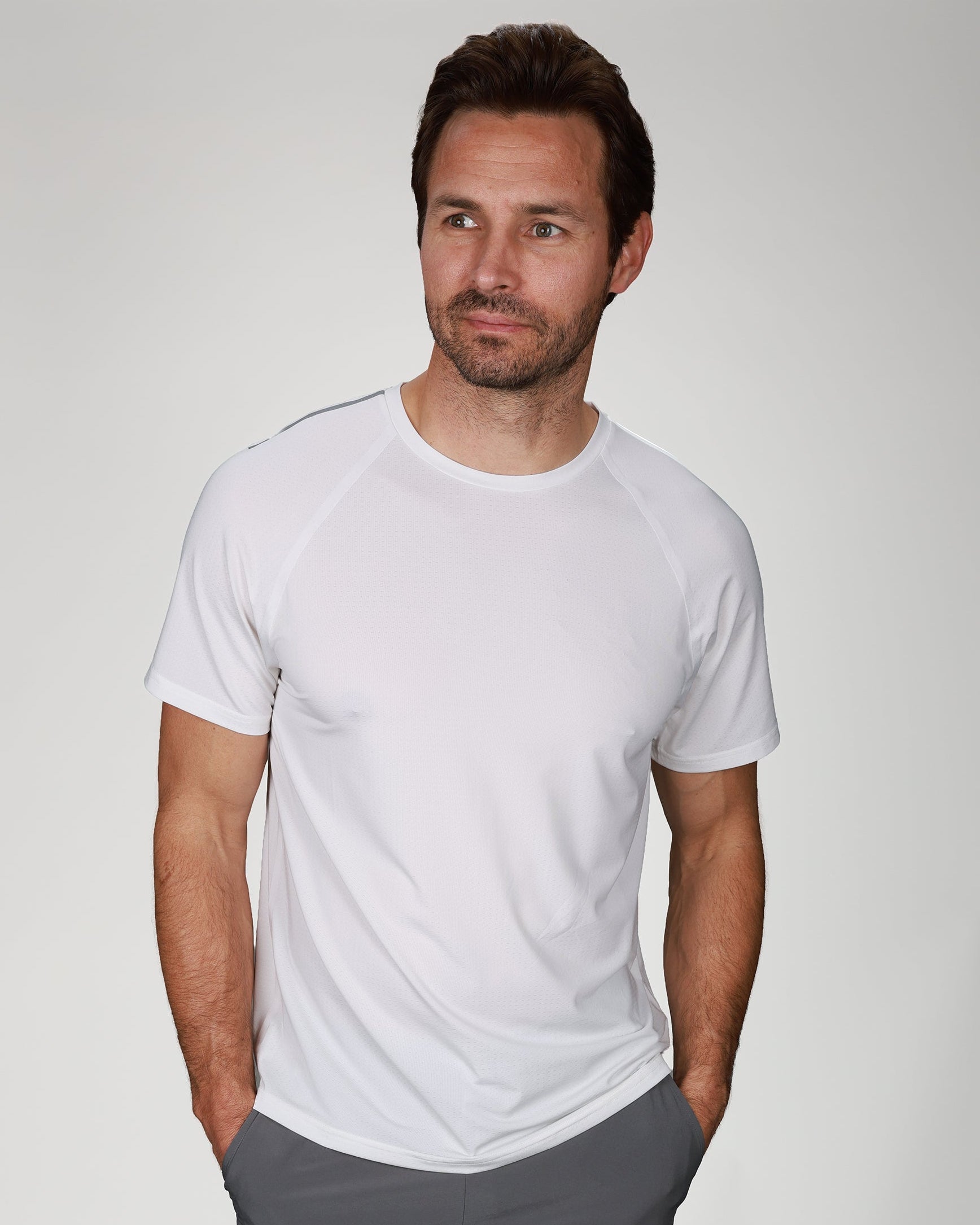 Man wearing a white t-shirt and gray shorts on a plain background