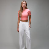 front of white pleated plant and coral baby tee