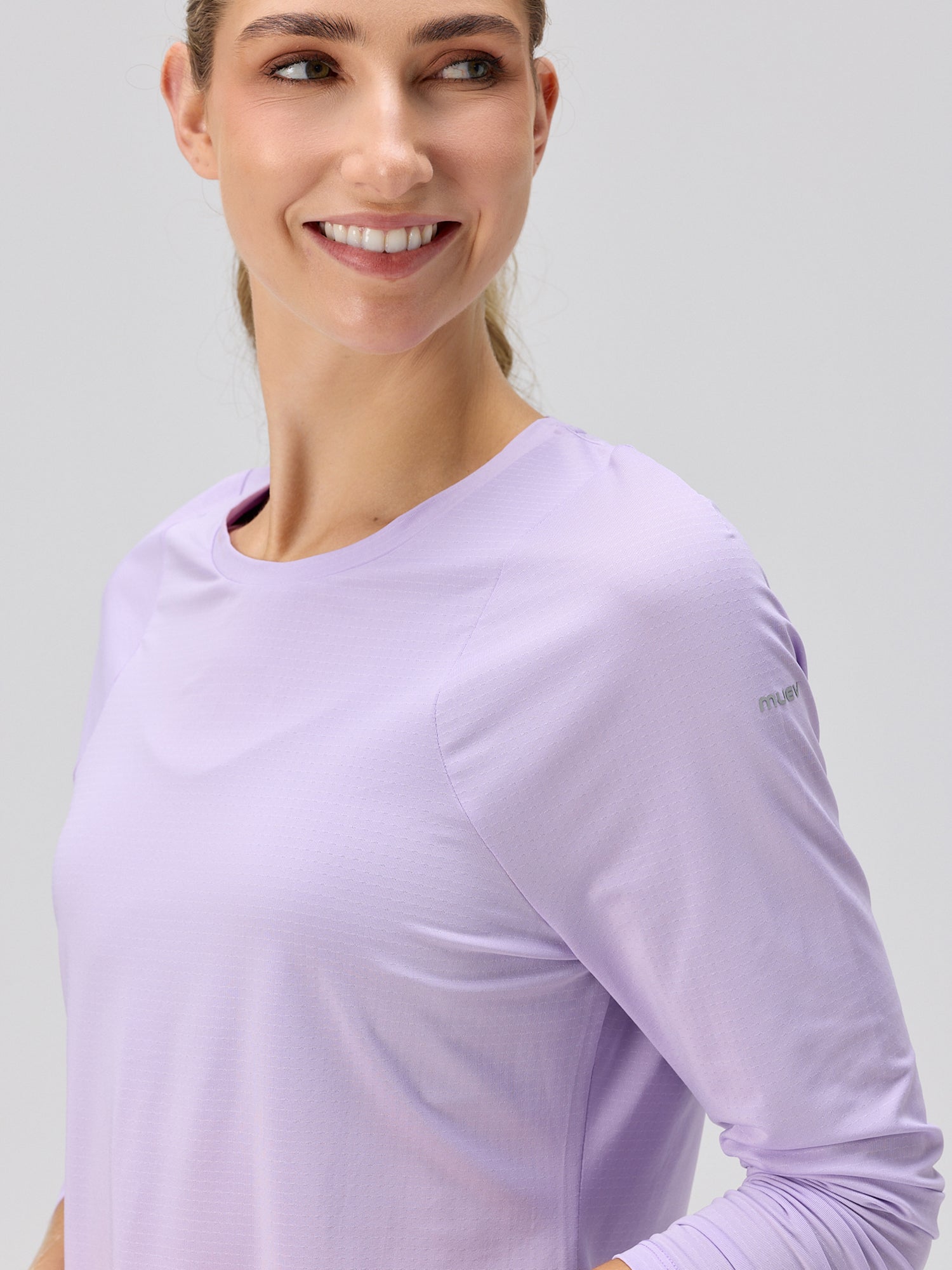 Woman wearing a lilac long sleeve performance top with SPF protection, designed for padel and pickleball apparel by MUEV.