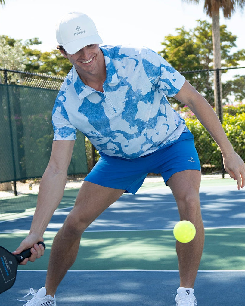man wearing a royal blue MUEV Base Line Short with 6-inch inseam and a blue and white patterned polo playing pickleball outdoors