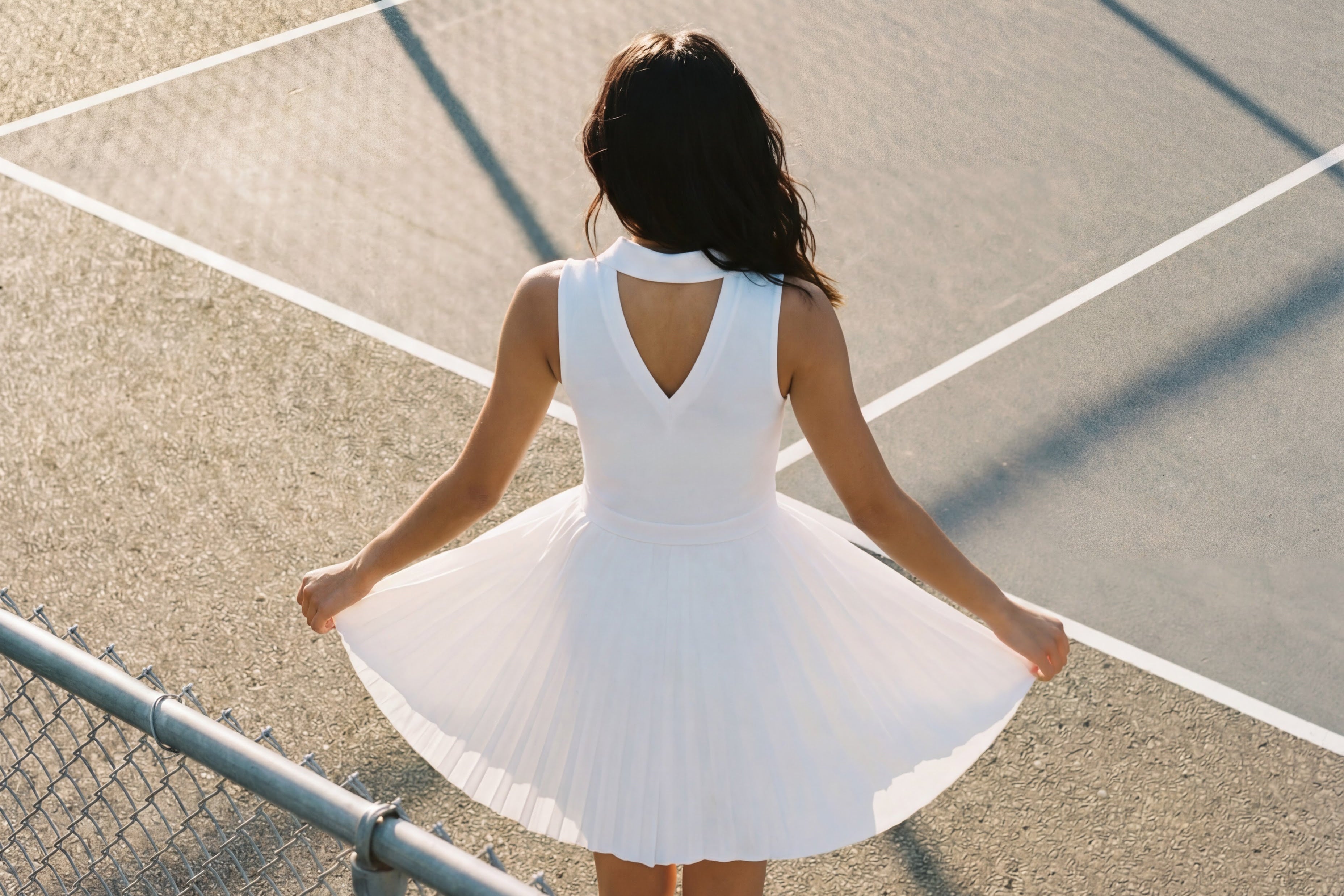 Woman in a white dress standing on a pickleball court
