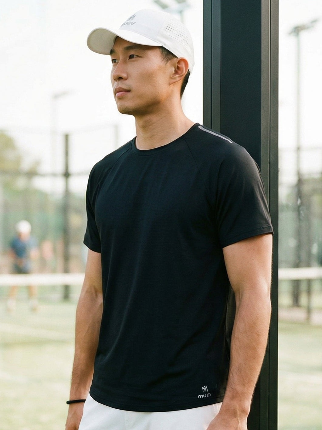 Man in black t-shirt and white shorts standing on a tennis court