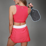 back of pink tanklette and pleated skirt