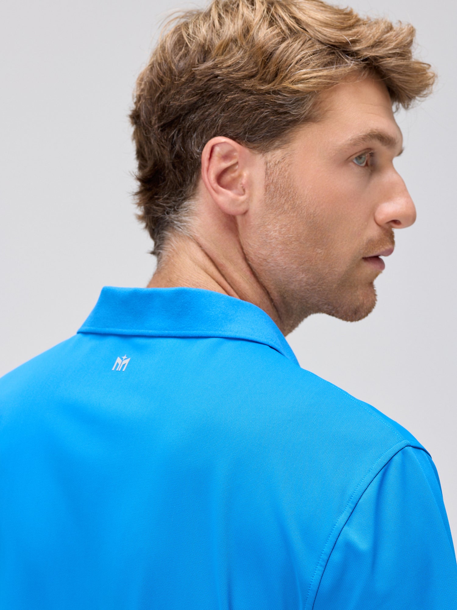 man wearing royal blue moisture-wicking polo designed for padel and pickleball with four-way stretch and SPF 50 protection viewed from the back